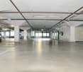 Large parking lot, concrete floor, white walls, open space, metal beams
