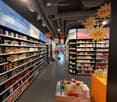 Aisle in a store with shelves full of perfume bottles, signs with discounts, and promotional items on display.