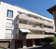 multi-storey building, balconies, beige and white walls, two garages