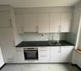 modern kitchen with white cabinets, black countertop, integrated oven and dishwasher, stainless steel sink with faucet