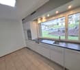 modern kitchen with tile flooring, white cabinets, double stainless steel sink, granite countertop, built-in oven and stove, large windows with view to outdoor area
