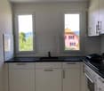 kitchen, tile flooring, white cabinets, black countertops, gas stove, dishwasher, windows
