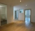 Empty room, wooden floor, white walls, two doors, one leading to a bathroom