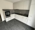 modern kitchen with white cabinets, black countertops, stainless steel oven, sink, faucet, tiled floor