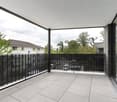 large balcony, black railings, tiled floor, glass walls, view of trees and buildings