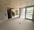 Empty room with concrete floor, unfinished walls, staircase, sliding glass door, and a small bowl on the floor.