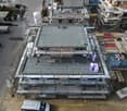 Aerial view of a house under construction with scaffolding, grey roof, and multiple levels.