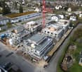 Aerial view of a construction site with multiple buildings under construction, surrounded by other buildings and greenery.
