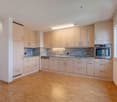 modern kitchen with wooden floors, white cabinets, granite countertops, built-in oven and dishwasher, large windows