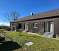 Modern house, brown walls, tiled roof, wooden fence, outdoor seating, garden, 3 windows