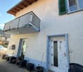 2-story house, white stucco wall, metal railing balcony, white door, multiple potted plants