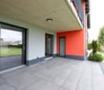 modern building, gray and orange walls, large glass doors, tiled floor, balcony