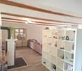 living room with wooden beams, fireplace, couch, wooden floor, white shelves, plants, lamp