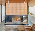 open fireplace with glass cover, stone hearth, brown leather armchairs, white walls, wooden ceiling