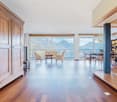 Hardwood floors, large windows, chandelier, large wooden cabinet, round dining table, striped chairs, side table
