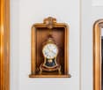 Ornate wooden clock with a gold-colored frame and decorative elements. The clock face displays the time.