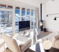 wooden floor, two sofas, two tables, large glass windows, fireplace, TV, remote control