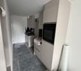 kitchen with white cabinets, black oven, sink, and countertop, grey floor, white walls