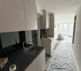 kitchen with white cabinets, black countertops, stainless steel sink, faucet, and a roll of tape on the counter