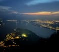 Aerial view of a city at night with a lake and mountains in the background