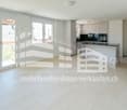 Open plan living room and kitchen, large windows, balcony, tiled floor, modern kitchen appliances