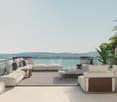 Outdoor living area with couches, center table, and decorative objects with a balcony overlooking water.