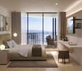 large bed, pillows, blankets, bedside tables, lamps, rug, large windows, balcony, chair, desk, picture frames, shelf