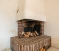 brick fireplace with stacked firewood and white ceiling