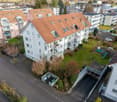 Aerial view of apartment complex with 4 levels, featuring balconies, common garden area, and parking