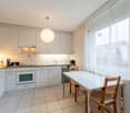 modern kitchen, white cabinets, tiled floor, kitchen island, oven, dishwasher, under-cabinet lighting, hanging lamp, coffee maker, toaster, microwave