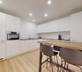modern kitchen with white cabinets, wooden countertop, stainless steel appliances, dishwasher, washing machine