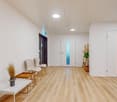 Empty hallway with a hardwood floor, three chairs and a coffee table, a plant in a pot, two doors