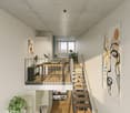 open floor plan, raised ground floor, stairs, desk with chair, balcony, kitchen, sink, stove, wine bottles, picture