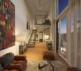 large open space with couch, living area, kitchen area, balcony, stairs to upper floor