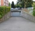 Asphalt parking lot with multiple parked cars, leading to a garage door.