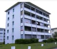 Multi-story apartment building, white exterior, many windows, balconies