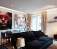 black couches, wooden floor, white walls, dining table, desk lamp, artwork, television