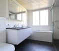 large shower, bathtub, white tiles, vanity, mirror, sink with two faucets, modern design