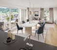 Open-plan living and dining area with large windows, balcony, modern furniture, kitchen island, and scenic view.