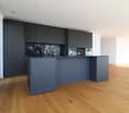 modern kitchen with island, black cabinets, wooden floor, large windows