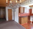 Chandelier, wooden cabinetry, tiled backsplash, modern oven, wooden flooring