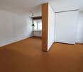 Empty room with white walls, wooden floors, central pillar, windows, sliding glass door