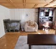 wooden floor, white walls, fireplace, wooden cabinet, armchair, coffee table, rug, stool