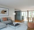 A modern living room with a grey sofa, wooden floor, glass coffee table, and floor lamp