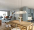 Dining area with wooden table, chairs, white vase with flowers, grey sofa, coffee table, cabinet, carpet, lamp, and picture frame on the wall