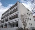 multi-story building, white exterior, balconies on each floor, modern design, multiple windows, metal railings