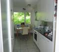 modern kitchen with white cabinets, tiled floor, dining table, chairs, large windows, view of trees