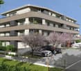 Modern apartment building with balconies, parking area, and landscaped garden