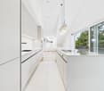 modern kitchen, white cabinets, white countertops, white tiled floor, large windows, balcony