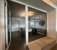 modern dining area with glass walls, wooden floor, table and chairs, built-in bench, mirrors on the wall